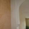 Pale terra cotta "distressed" finish wall flush with natural plaster arch.
